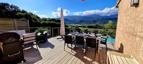 une terrasse en bois avec une table et des chaises sur un balcon dans l'établissement Villa Bella Vista, 4ch, piscine, à Figari