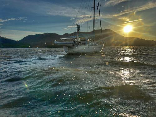 a boat in a body of water with the sun setting at Yellow house 6 minutos de playa in Barra de Navidad