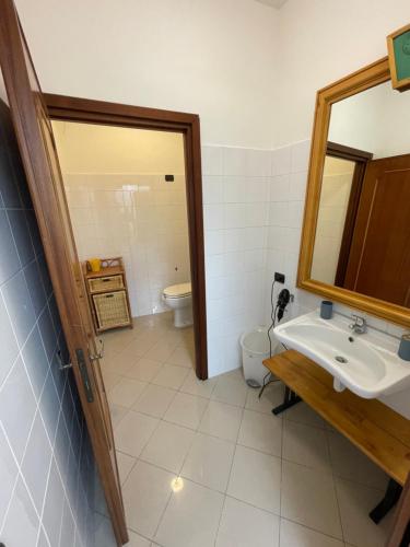 a bathroom with a sink and a toilet and a mirror at Casa Vacanze Rosarlo in Nettuno
