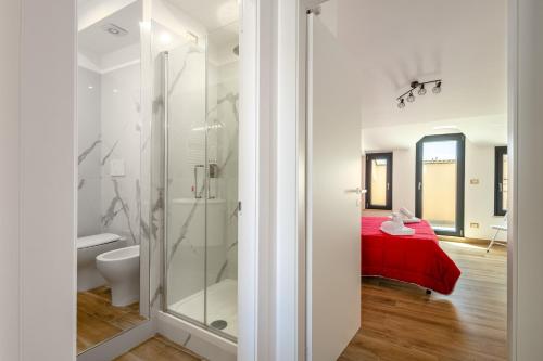 a bathroom with a shower and a red bed at Rosso Rubino - Mansarda Vista Lago a Marta in Marta
