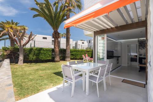 a white table and chairs on a patio with palm trees at Apartamerica 341 LujoVista Mar in Playa de las Americas