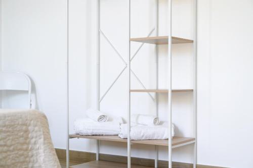 a white book shelf with towels on it in a bedroom at Esmeralda - Mansarda con vista mozzafiato in Marta
