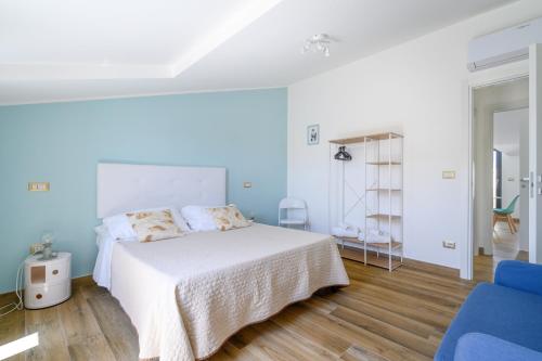 a bedroom with a white bed and a blue chair at Esmeralda - Mansarda con vista mozzafiato in Marta