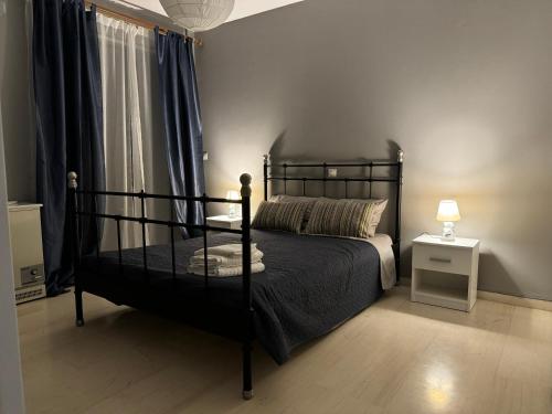 um quarto com uma cama preta e uma mesa de cabeceira em WINDSOR PLACE APARTMENT - VOULIAGMENI em Atenas