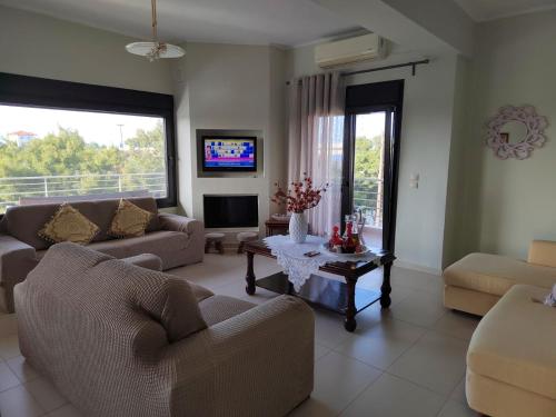 a living room with two couches and a tv at The house next to the canal ! in Nea Moudania