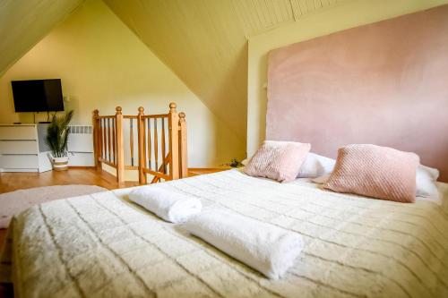 um quarto com uma cama com lençóis brancos e almofadas cor-de-rosa em Aparteo Apartament na Polanie em Kościelisko