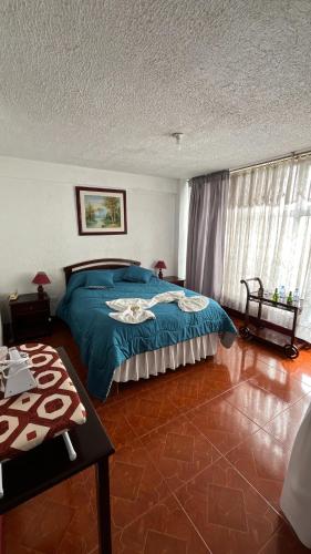 a bedroom with a blue bed and a table at Hotel Espindola in Tulcán