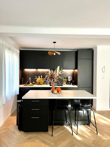 une cuisine avec des armoires noires et un comptoir blanc dans l'établissement Appartement Roucas - Corniche, à Marseille