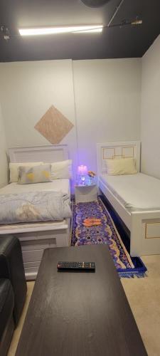 um quarto com duas camas e uma mesa com controlo remoto em MAMA DELIGHT GUEST ROOM em Abu Dhabi