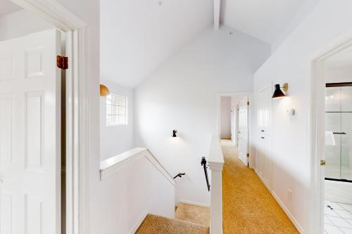 a hallway with white walls and a white stairway at Victorian Dream in Arroyo Grande