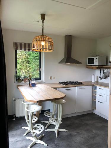 a kitchen with a wooden table and a pendant light at Have a nice stay! - Holiday Home de Witte Raaf with garden and hottub in Noordwijk aan Zee