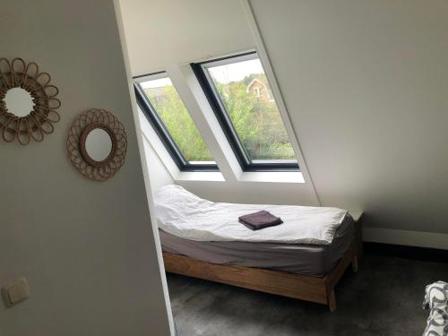 a small bedroom with a bed and two windows at Have a nice stay! - Holiday Home de Witte Raaf with garden and hottub in Noordwijk aan Zee