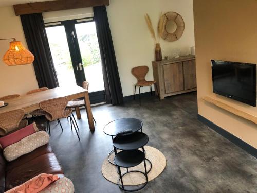 a living room with a couch and chairs and a television at Have a nice stay! - Holiday Home de Witte Raaf with garden and hottub in Noordwijk aan Zee