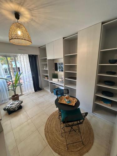 - un salon avec une table, des chaises et des étagères dans l'établissement Studio Emeraude à Cavalaire, à Cavalaire-sur-Mer