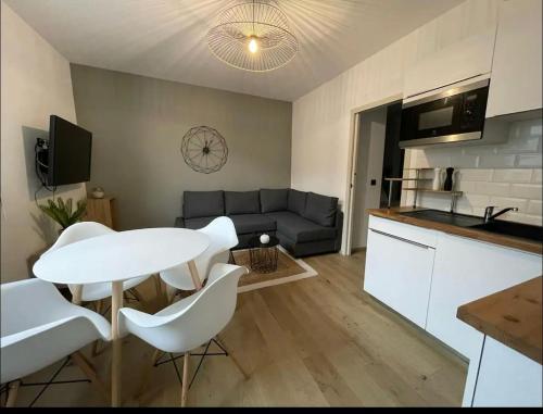 Il dispose d'une cuisine et d'un salon avec une table et des chaises blanches. dans l'établissement La Belle Échappée, à Lourdes