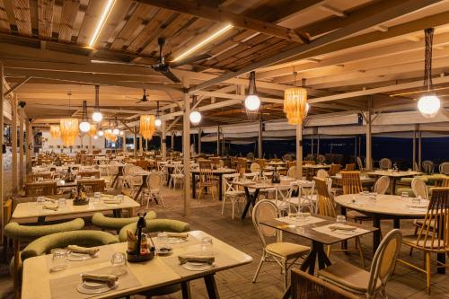 a restaurant with tables and chairs and lights at Zoe Hotel, Trypiti Beach Resort & Hive water park in Limenaria