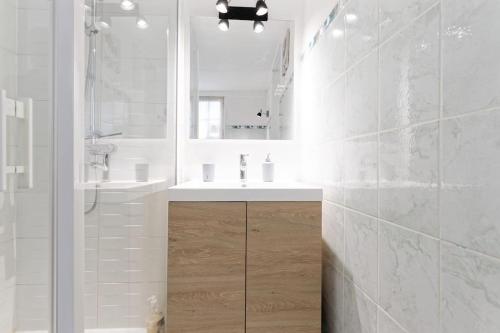une salle de bain blanche avec un lavabo et un miroir dans l'établissement Bienvenue chez vous, à Honfleur