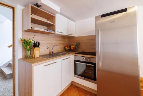a kitchen with white cabinets and a stainless steel refrigerator at Apartmani Anđelić- Fužine 1 in Fužine