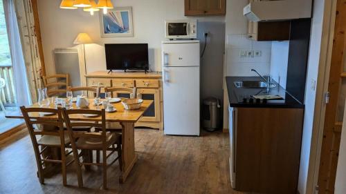 Il comprend une cuisine équipée d'une table avec des chaises et d'un réfrigérateur blanc. dans l'établissement Résidence Les Terrasses De La Bergerie - Deux pièces cabine 6 personnes Terrasses de la Bergerie MAE-1731, à Orcières