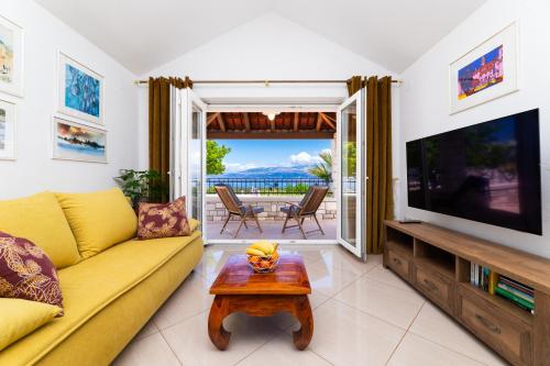 a living room with a yellow couch and a flat screen tv at VILLA AGAPE - Three bedroom villa on 15k m2 olive grove - Incredible 360 view - Free parking - Private pool and jacuzzi in Mirce