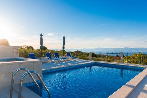 uma piscina com espreguiçadeiras e vista para o oceano em VILLA AGAPE - Stone villa on 15k m2 olive grove - Incredible 360 view em Mirce