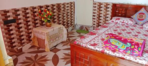 een slaapkamer met een bed en een tafel met een vaas met bloemen bij Happy Morning Rohini Homestay in Kurseong
