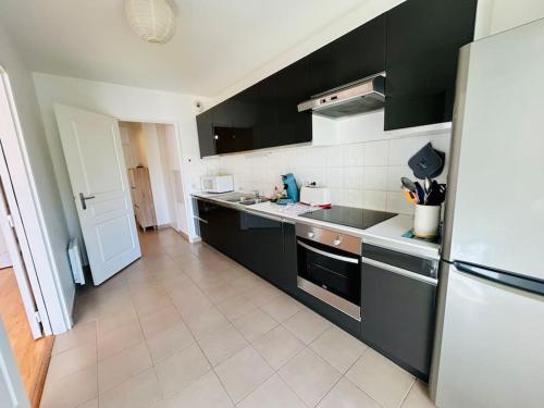 Il comprend une cuisine avec des placards noirs et du carrelage blanc. dans l'établissement T3/4-6pers/5'piedplage/centreville/parking/wifi, à Arcachon