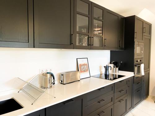 een keuken met zwarte kasten en witte aanrechtbladen bij Great Duplex Apartment in Marbesa in Marbella