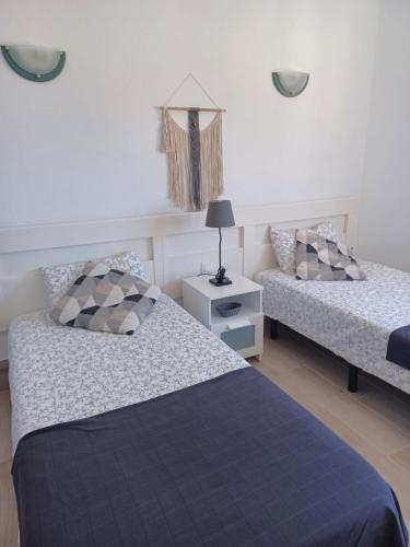 a bedroom with two beds and a table with a lamp at Apartamento con vistas a la playa, Puerto Rico in Puerto Rico de Gran Canaria