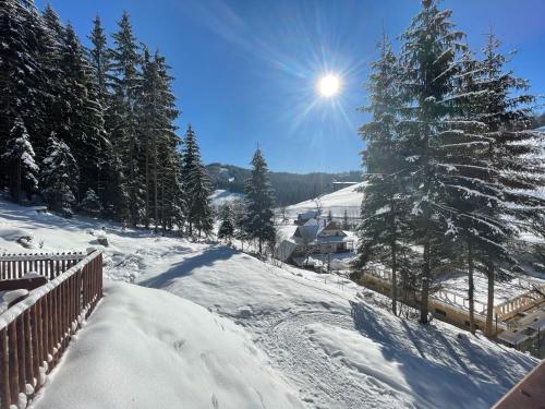 a snow covered hill with a fence and a tree at Chalupa na Leskové in Velké Karlovice