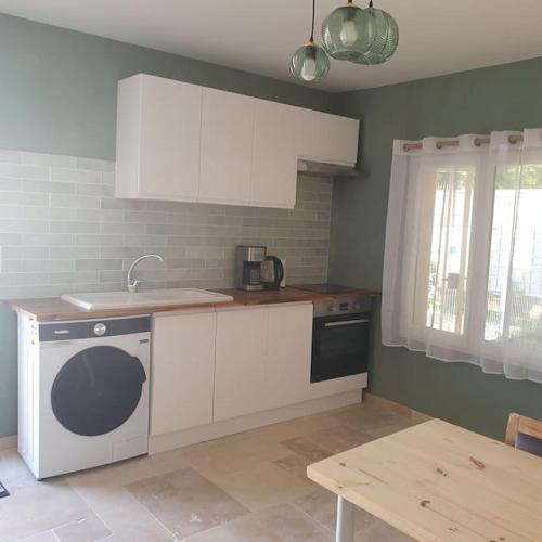 une cuisine avec des armoires blanches, un évier et un lave-vaisselle dans l'établissement Le Havre des cascades, à Sabran