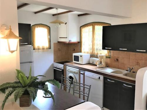 - une cuisine avec un évier et un comptoir avec une table dans l'établissement APPARTEMENT de 50m2 en rez de jardin - 3 étoiles, à Porto-Vecchio