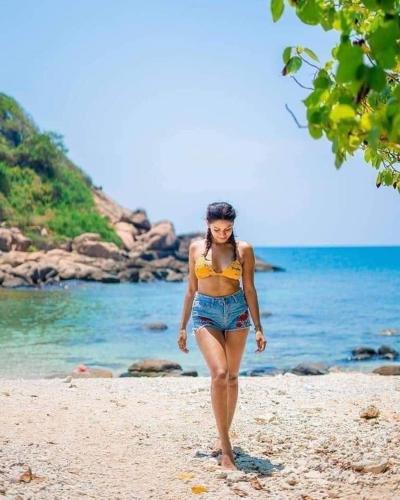 a woman walking on a beach near the water at Nilaveli Guest House in Nilaveli