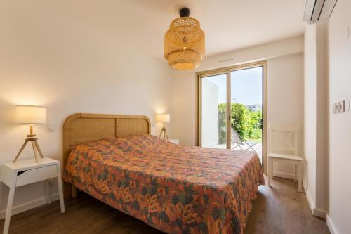 une chambre avec un lit et une grande fenêtre dans l'établissement Antibes Rez de Jardin, grande terrasse dans résidence avec piscine, à Antibes