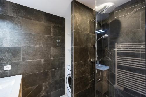 une salle de bain avec une douche avec une porte vitrée dans l'établissement Antibes Rez de Jardin, grande terrasse dans résidence avec piscine, à Antibes