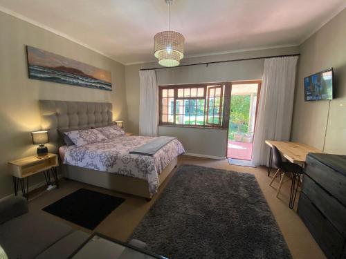 Un dormitorio con una cama y una ventana y una mesa. en Garden Home in Upper Walmer, en Gqeberha