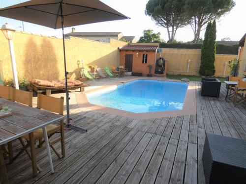 - une piscine avec un parasol sur une terrasse en bois dans l'établissement Maison TOMASELLO, à Carcassonne