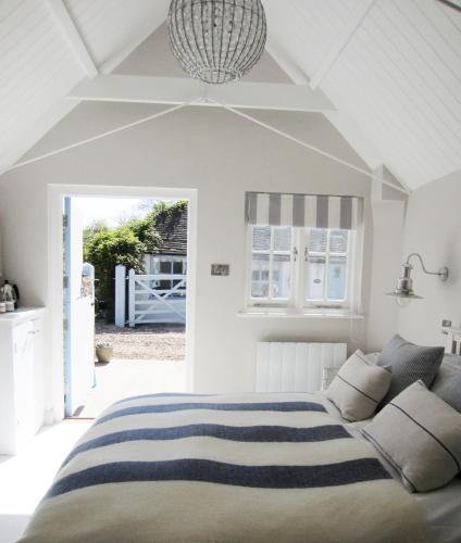 a white bedroom with a bed and a couch at The Sailor's House at Blue Door Barns in Beddingham