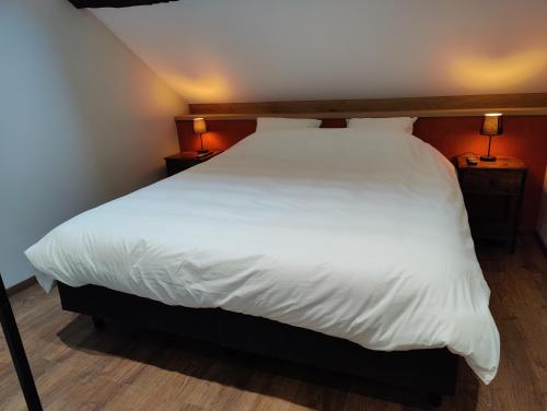 um quarto com uma cama com lençóis brancos e 2 candeeiros em Le Saint Michel em Rochefort