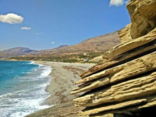 a rock wall next to a beach with the ocean at Melina Apartment - Akoumia Village in Akoumia