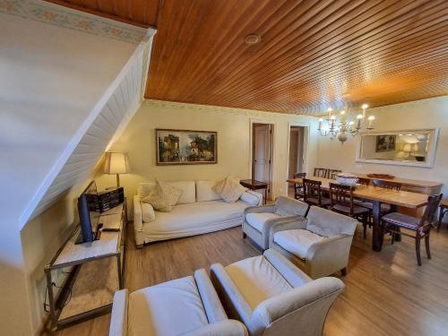 a living room with white furniture and a wooden ceiling at Apartamento parque capivari no centro de capivari in Campos do Jordão