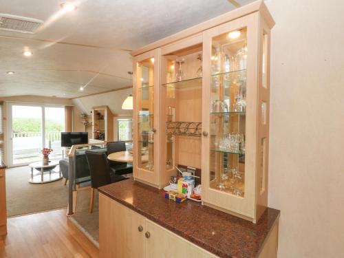 a kitchen with a china cabinet with glass doors at Coed Llai Lodge in Holyhead