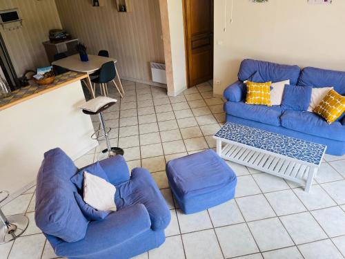 a living room with two blue couches and a table at Les Gîtes de Yanaely - L'Ibie in Juignac