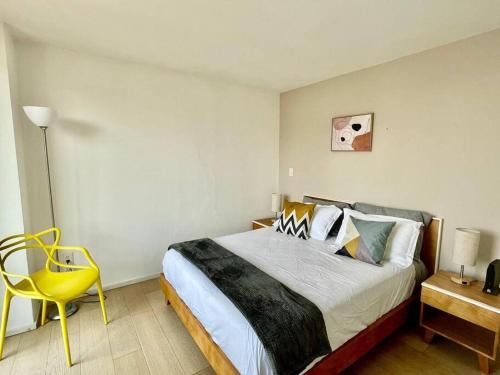 a bedroom with a bed and a yellow chair at Moderno departamento en centro histórico in Mexico City