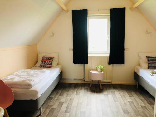 two beds in a room with a window at Vrij uitzicht Texel in De Koog