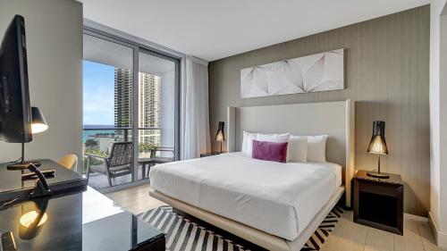 ein Schlafzimmer mit Bett und Schreibtisch und ein Balkon in der Unterkunft Elegance by the Ocean - 2BD Hyde House Gem with LUXURY RESORT AMENITIES in Hollywood