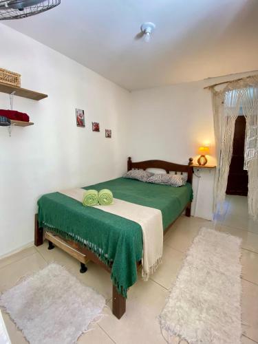 a bedroom with a bed with a green blanket at Apartamento no centro para Casal in Mata de Sao Joao