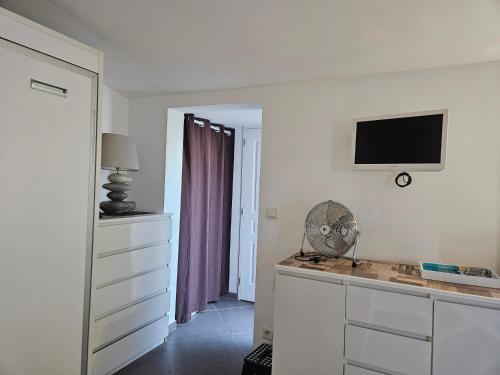 une pièce blanche avec un bureau avec un ventilateur et une télévision dans l'établissement entre mer et montagne, à Saint-Estève