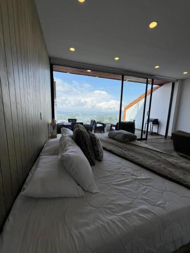 a large white bed in a room with a large window at Montecielo Hosting in Guatapé