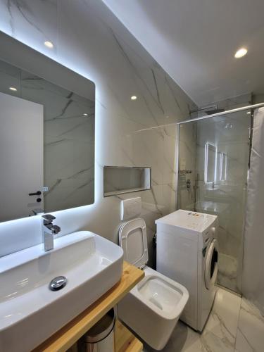 a white bathroom with a sink and a toilet at Jani Studio Apartments in Gjirokastër